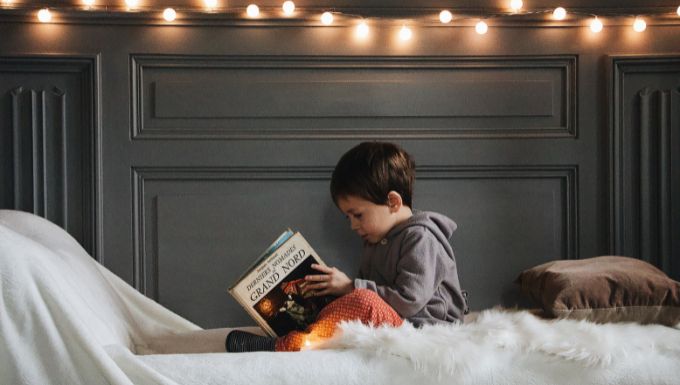 Boy reading book on bed