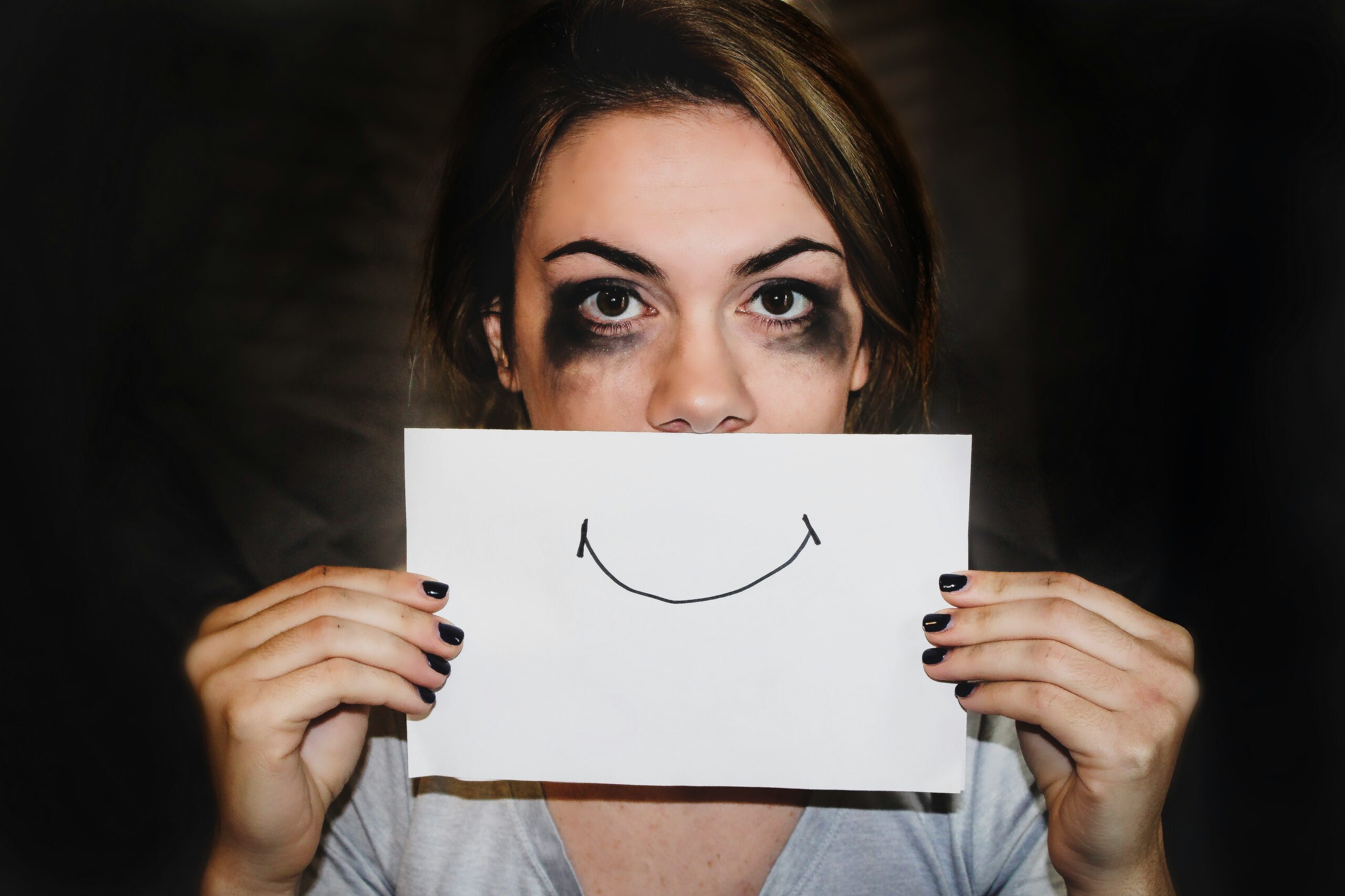 a woman holding a piece of paper with a smiley face drawn on it emotional intelligence